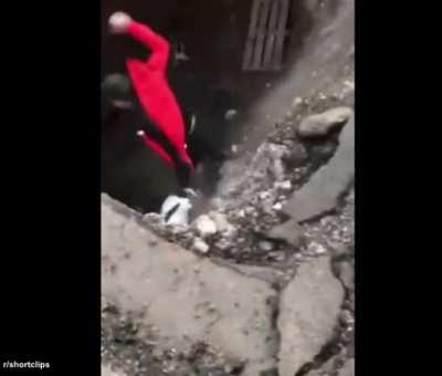 Pedestrian looks into a deep hole, then loses balance