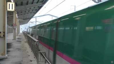 E5 Shinkansen passes through a snowy station in winter in Japan.