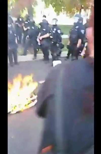 Anti-police protestor burns Blue Lives Matter flag inches away from police line