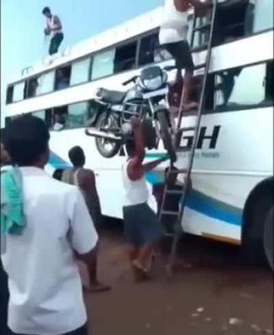 Carrying a motorcycle up a ladder like it's nothing!