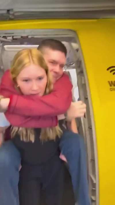 Daughter carrying her disabled father from his seat to his wheelchair.