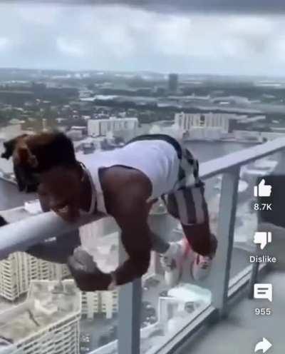 Rapper with a gun hanging on the side of a building