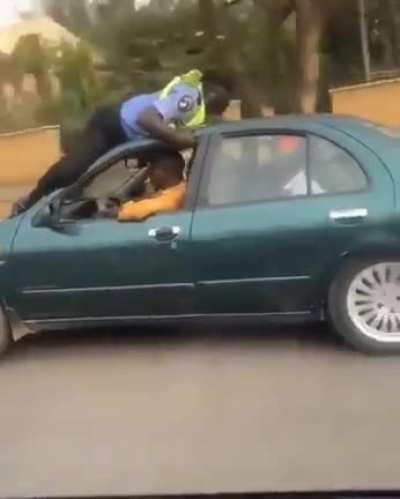Driver refuses to stop as a traffic warden jumps in front of his car for allegedly violating traffic laws, in Nigeria.