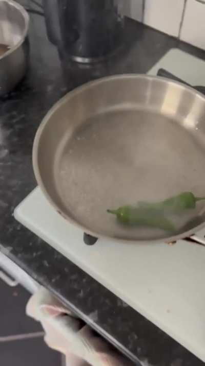 Putting wet chillies in a scotching hot pan while recording a cooking video