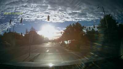 Idiot on a bike flies through an intersection while the sun is blinding all of the cars going though the intersection.