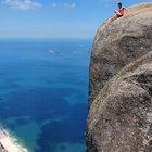 A tourist sitting on top of the Pedra da Gávea Mountain, Brazil