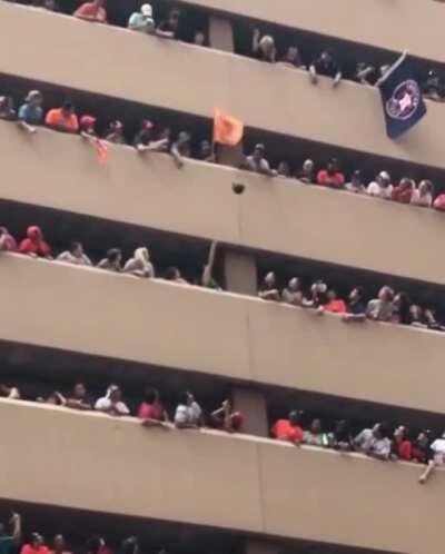 People tossing a hat up to the lady who dropped it at an Astros World Series parade.