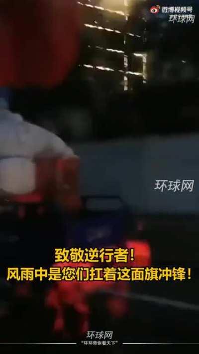 Communist health workers driving through the rain with the FLAG against the storm.