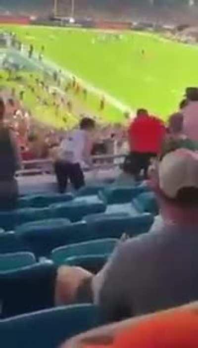 Fans use flag to catch falling cat during a college football game.