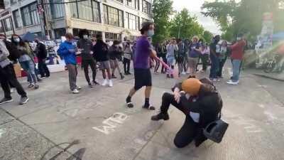 Person walking around CHAZ in Seattle wearing a Donald Trump mask offering people to beat him with a noodle