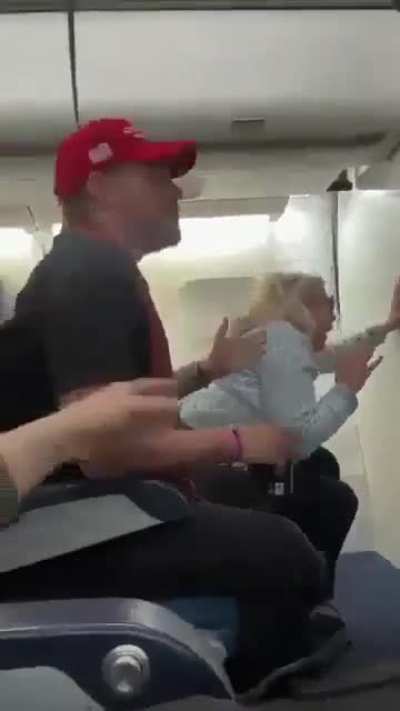 Woman freaks out sitting next to MAGA hat wearing man
