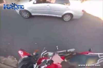 Speeding biker flips the bird at motorist then treats his knee cap to a street bin.