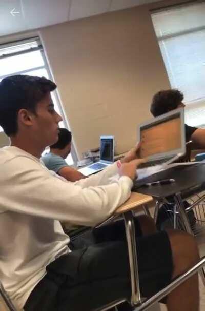 Guy folds his apple macbook backwards while in the middle of a class
