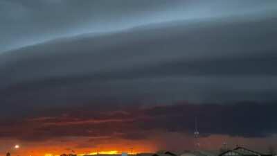 A huge Shelf cloud with a golden/red sunset in the background