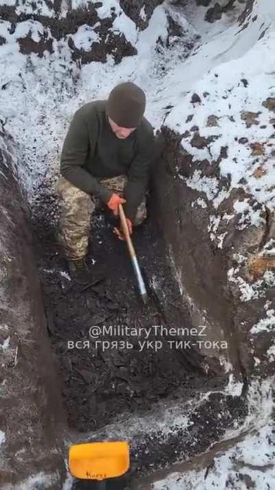 RU POV: Ukrainian soldier using an axe to dig a trench