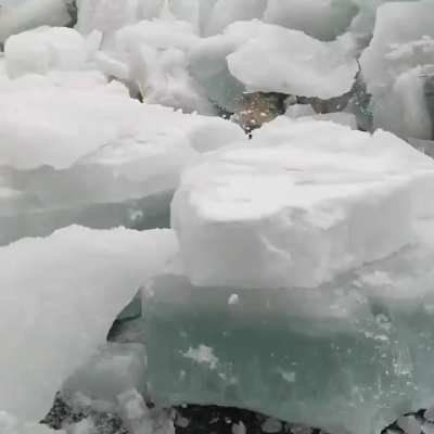 A dramatic ice shove where powerful winds and pressure force huge slabs of river ice onto the shoreline.