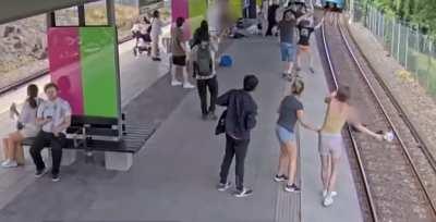 Insane woman pushes elderly man onto the train tracks