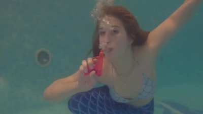 Pretty mermaid blows bubbles on a gun
