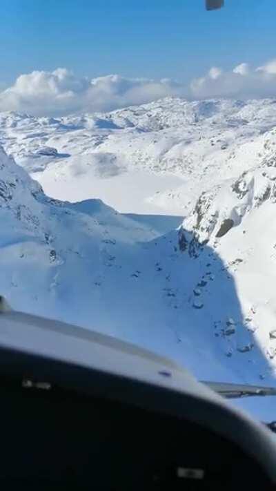 Flying around the snowy hills on approach in a valley. Southern Norway