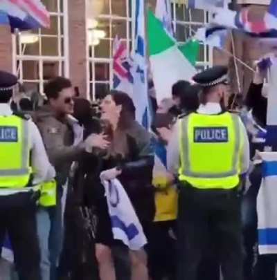 A woman among pro-Israel crowd making threatening gestures toward Palestine supporters.