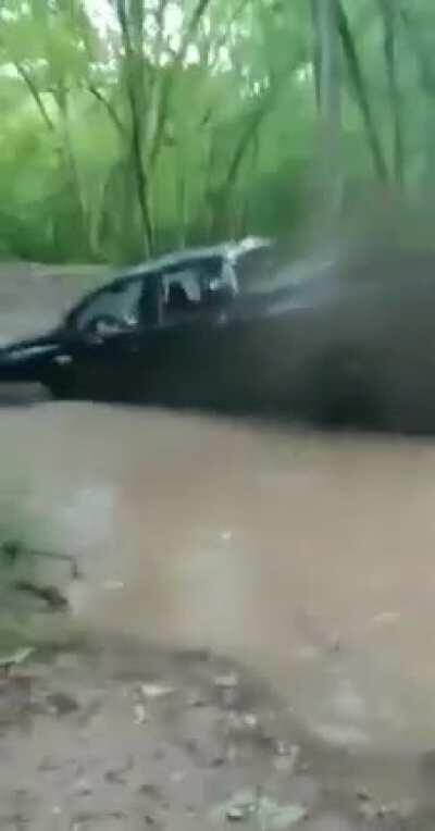 Idiot gets car stuck while trying to cross a stream. What was he thinking?