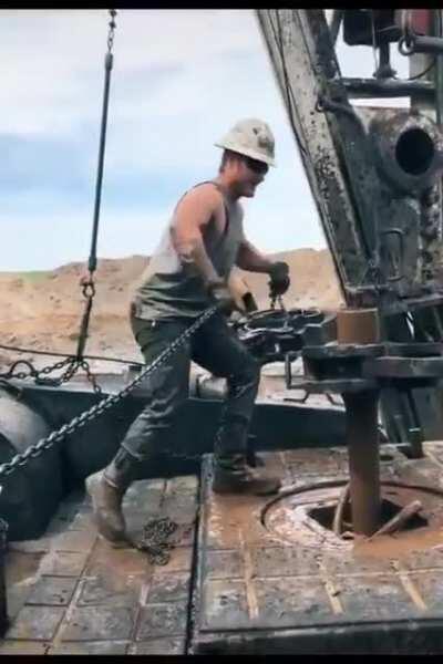 Oil rig worker ”throwing the chain” (a dangerous method of connecting the drill pipes)