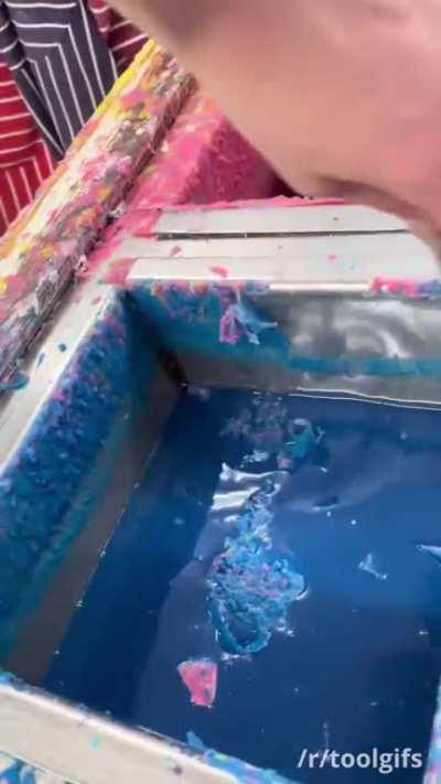 Scraping wax off a candle carving dip tank