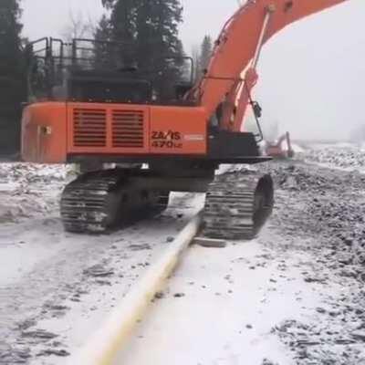 Excavator hopping over a pipe