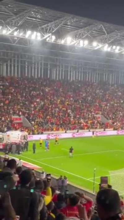 Supporter breaks corner post on goalkeeper's back.
