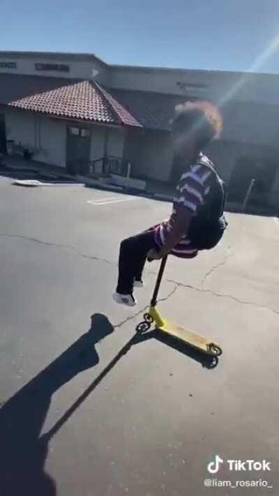 Guy riding a scooter on its handlebars.