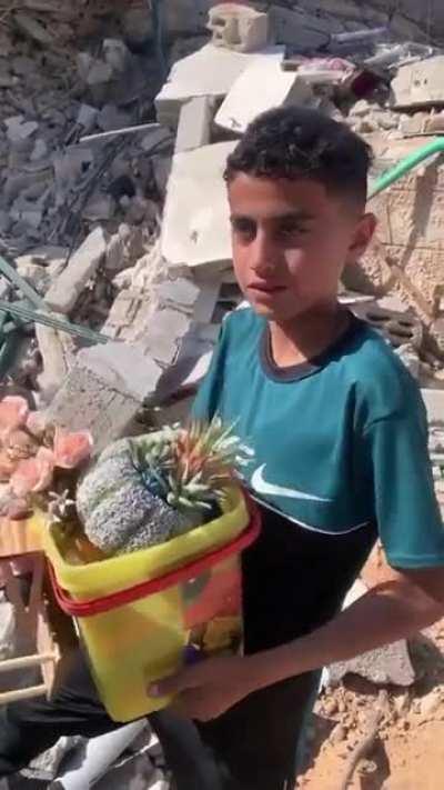 A child in Gaza Puts what's left of his childhood into a bucket after Israeli Airstrikes Leveled his home