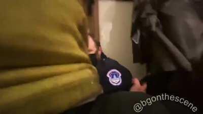 An officer quakes in fear as the crowd rushes past, pushing officers against the wall inside the U.S. Capitol Building