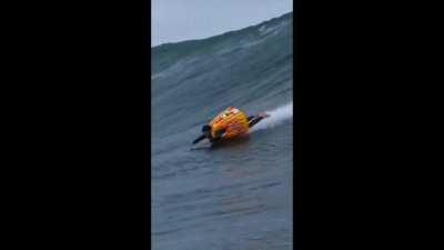 A man rides a huge wave using a customized inflatable surf vest.