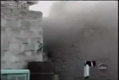 A marine throws a grenade at an Iraqi insurgent who fell down between two buildings, and then finishes him with his rifle.