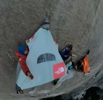Mountain climbers sleep while suspended to a rock wall