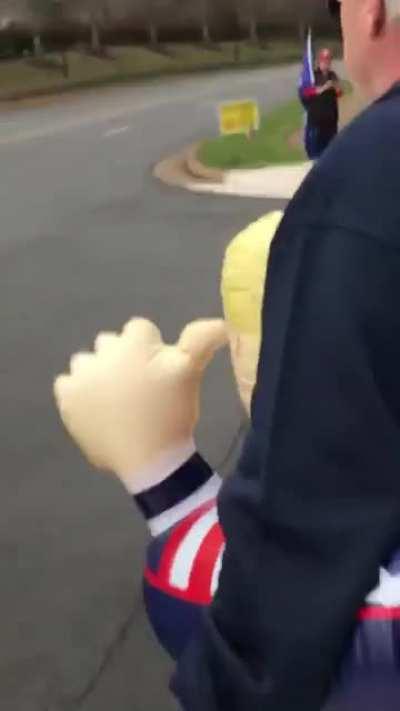 Man wearing Trump floaty coughs on people protesting outside Trump golf course.