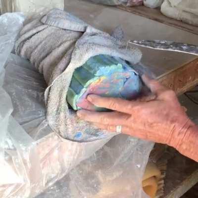 Cutting through clay with a wire to reveal art