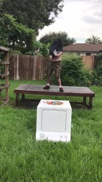 Guy jumps onto a washing machine with predictable results