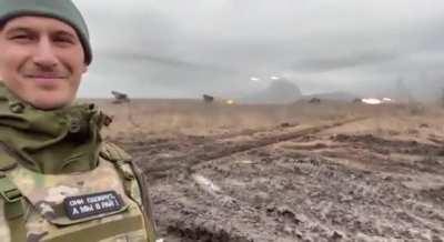 Russian soldier smirking as rockets fly in the background