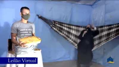 A priest doing an online auction of a lasagna while swinging on a hammock