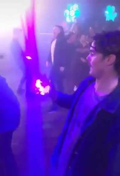 This guy lines his drink up with a light in a club perfectly
