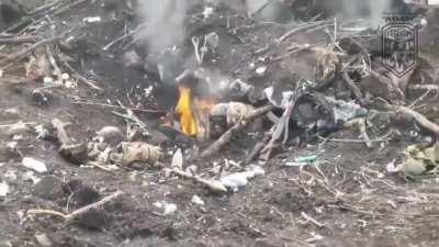 Russian soldier climbs out of a burning hole and collapses after a Ukrainian drone dropped an explosive inside. His comrade is on fire next to him.