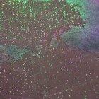 Lights at a botanical garden reflecting onto a puddle while raindrops fall onto it, look like mini fireworks