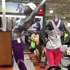 Group of women steal hoards of clothes, pushes security guard, and leaves a trail of clothes on the ground while escaping in vehicle.