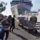 Several people are almost crushed by a ship that crashes against a docked boat