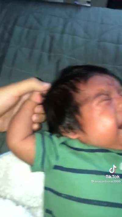 Baby is crying because he is pulling his own hair