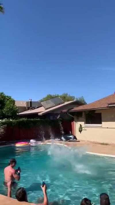 A couple backflipping into a pool together