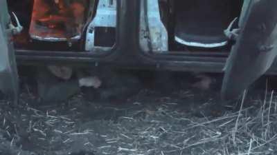 Russian soldiers are hiding under a destroyed and burning infantry fighting vehicle.