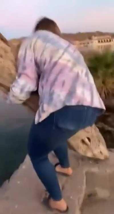 Throwing a log of wood standing on the edge of a lake (original video)