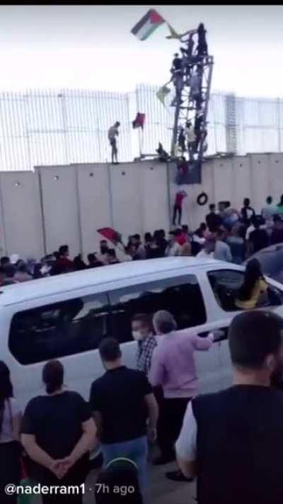 Lebanese protesters climb a section of the border wall and voice their support for the Palestinian struggle